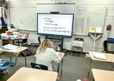 classroom with student at desk in front of distance learning board